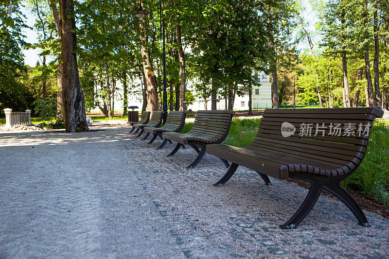 Alley with brown wooden benches in a park in Kemeri, Latvia.